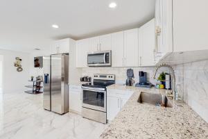 uma cozinha com armários brancos e um frigorífico de aço inoxidável em Seaview Suite em Deerfield Beach