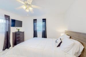 um quarto com uma cama branca e uma ventoinha de tecto em Seaview Suite em Deerfield Beach