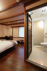 a bedroom with a bed and a bathroom with a sink at Kyomachiya Ryokan Sakura Urushitei in Kyoto