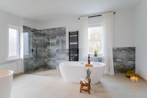 La grande salle de bains blanche est pourvue d'une baignoire et d'une douche. dans l'établissement CHALET627, à Braunlage