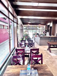 Sauraha Holiday Home Riverside في شيتوان: مطعم بطاولات وكراسي خشبية ونوافذ