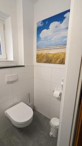 a bathroom with a toilet and a painting on the wall at "Haus zwischen Nord- und Ostsee" in Büdelsdorf