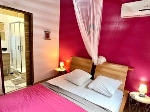 a bedroom with a bed with a pink wall at Villa Coco in Deshaies