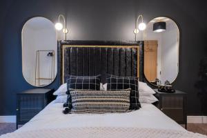 a bedroom with a large bed with two mirrors at Penthouse Noir - Wyndale Living - Central BHam 2BR in Birmingham
