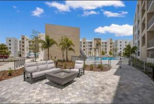 eine Terrasse mit einem Sofa und Stühlen vor einem Gebäude in der Unterkunft Condo Cuteness with Stellar View ~ On The Water & Perfectly Located in Sarasota