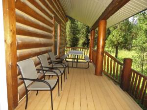 una terraza de madera con sillas y mesas. en The Hideaway Hostel en Island Park