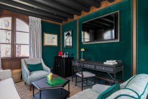 sala de estar con una pared verde y TV en Hotel Casa Palacio Don Ramón, en Sevilla