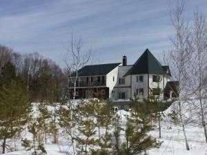 a large white house with a green roof in the snow at Pension Landscape Furano in Kami-furano