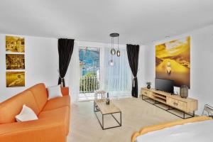 a living room with an orange couch and a tv at Apartments Casa Mia in Kotor