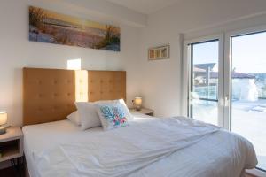 een slaapkamer met een wit bed en een groot raam bij Rtina Appartements in Rtina