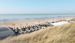 a beach with a lot of umbrellas and the ocean at Luxury apartment in farmhouse near Amsterdam in Ilpendam