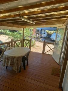 a wooden deck with a table and a tent at Mobil home 4 personnes in Saint-Paul-lès-Dax