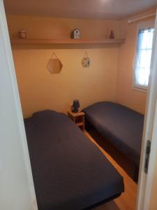 Duas camas num pequeno quarto com uma janela em Mobil home 4 personnes em Saint-Paul-lès-Dax