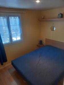a bedroom with a blue bed and two windows at Mobil home 4 personnes in Saint-Paul-lès-Dax