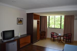 un soggiorno con TV e tavolo con sedie di Federal Hotel Kangar Perlis a Kangar
