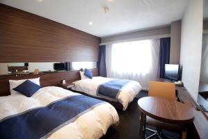 a hotel room with two beds and a table at Hotel Il Credo Gifu in Gifu