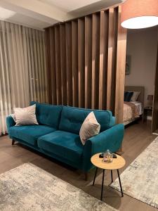 Apartmani SOVA في نوفي بازار: غرفة معيشة مع أريكة زرقاء وطاولة