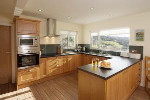 a kitchen with wooden cabinets and a stove top oven at Lang Parrock, Little Langdale in Little Langdale