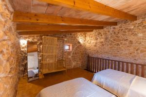 een slaapkamer met 2 bedden in een stenen gebouw bij Villa Petita Llombards in Llombarts