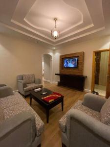 a living room with two couches and a flat screen tv at فخامة الجوهرة للشقق المخدومة ــــ للعائلات فقط ـــــ in Jeddah