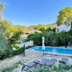 a swimming pool with chairs and an umbrella and a swimming pool at Maison & Jardin Coeur Luberon classé 4 étoiles in Peypin-dʼAigues