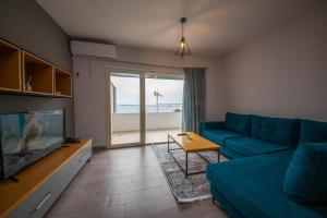 a living room with a blue couch and a view of the ocean at Aerial Hotel & Spa in Vlorë