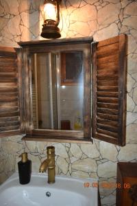 een wastafel in de badkamer met een spiegel en een raam erboven bij Angel's Traditional House 