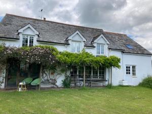 een wit huis met een bank en stoelen in de tuin bij Rural Devon retreat in stunning Exe Valley. in Exeter