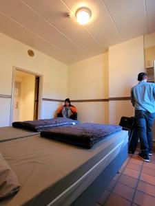 zwei Männer stehen in einem Zimmer mit zwei Betten in der Unterkunft Auberge de Jeunesse de Bouillon in Bouillon