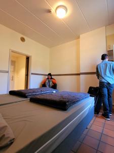 Dos hombres parados en una habitación con dos camas en Auberge de Jeunesse de Bouillon, en Bouillon