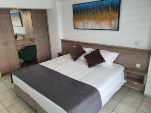 sypialnia z dużym białym łóżkiem z brązowymi poduszkami w obiekcie Larnaca Bay Suites w Larnace