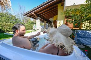 un hombre en una bañera con una copa de vino en DesenzanoLoft Luxury suite with jacuzzi and garden, en Desenzano del Garda