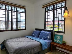 Schlafzimmer mit einem Bett mit blauen Kissen und Fenstern in der Unterkunft Grand Height Homestay 3A 10pax 4Rooms in Sibu