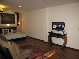 Sala de estar con cama y mesa con TV en QG Resort en Lat Krabang