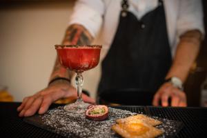 a man is standing next to a drink on a table at Erato by Samian Mare in Karlovasi