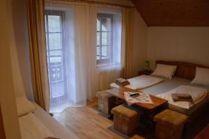 スタラー・リュボフニャにあるPenzión Dindaのベッドルーム1室(ベッド1台、テーブル、窓2つ付)