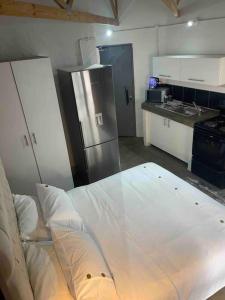 a kitchen with a white bed and a refrigerator at Dream Abodes at Cozy Craftmans Ship, Maboneng in Johannesburg