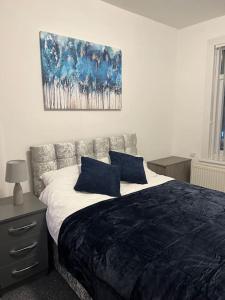 a bedroom with a bed with two blue pillows at Spacious 3 bed flat near Watford Junction in Watford