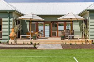 a house with two umbrellas on a wooden deck at Coastal Cool -Pool, Tennis Court in Sorrento