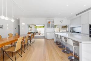 a white kitchen with a long table and chairs at Coastal Cool -Pool, Tennis Court in Sorrento