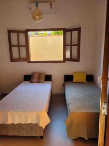 2 camas en una habitación con ventana en Linda Casa de Campo Nova em condomínio, en Porangaba