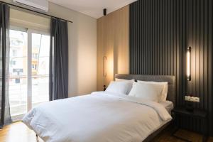 um quarto com uma grande cama branca e uma janela em Callirhoē Luxury 2BD Acropolis Apartment em Atenas