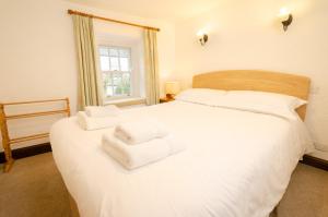 Un dormitorio con una cama blanca con toallas. en Nans, Elterwater, en Chapel Stile