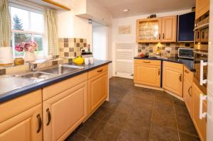 cocina con armarios de madera, fregadero y ventana en Nans, Elterwater, en Chapel Stile