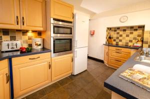 a kitchen with wooden cabinets and a white refrigerator at Nans, Elterwater in Chapel Stile