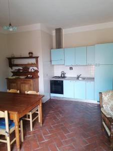 PolveretoにあるCasa Rossaのキッチン(青いキャビネット、木製テーブル付)