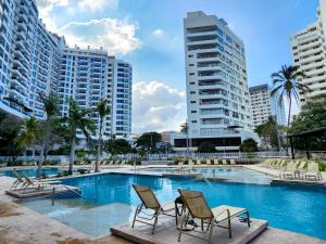 una piscina con 2 sillas y edificios en Apartamentos en Reserva del Mar - By BEDVIAJES, en Santa Marta