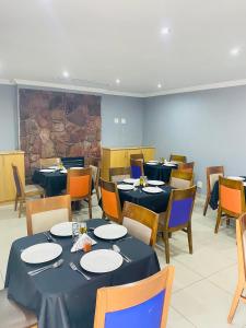 a dining room with blue tables and chairs and a stone wall at Munisa Guest House in Johannesburg
