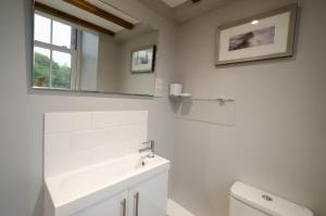 a white bathroom with a sink and a mirror at Cherry Tree Cottage in Chapel Stile