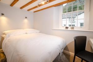 a white bedroom with a bed and a desk and a window at Cherry Tree Cottage in Chapel Stile